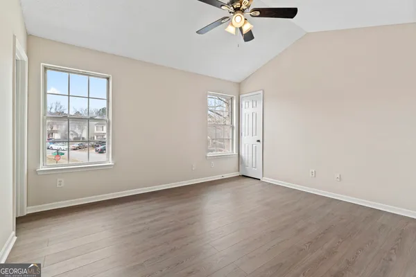 an empty room with wooden floor chandelier fan and windows