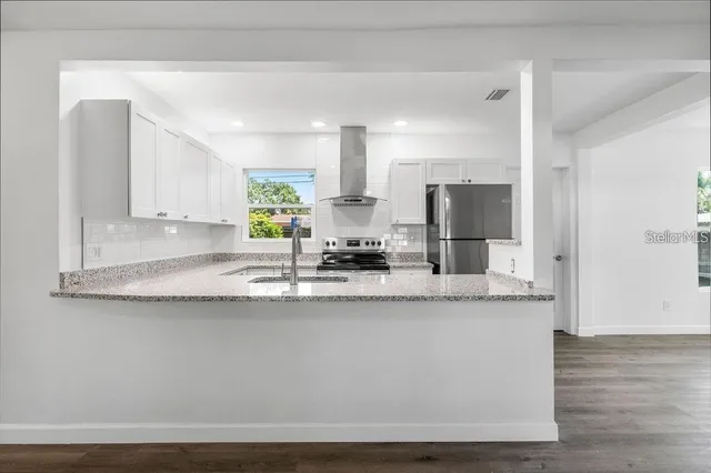 a kitchen with stainless steel appliances granite countertop a sink a stove and a refrigerator