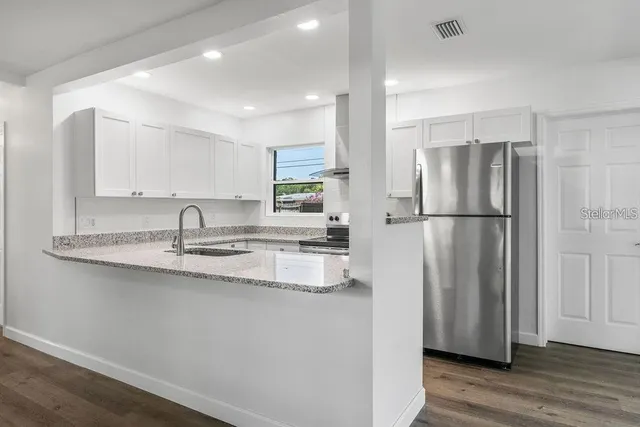 a kitchen with stainless steel appliances granite countertop a refrigerator a sink and a refrigerator