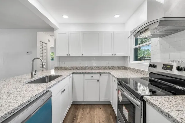 a kitchen with granite countertop a sink stove and cabinets