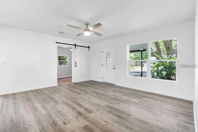 a view of empty room with wooden floor and fan