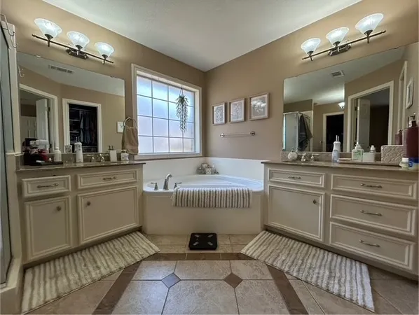 a spacious bathroom with a granite countertop sink mirror and a bathtub