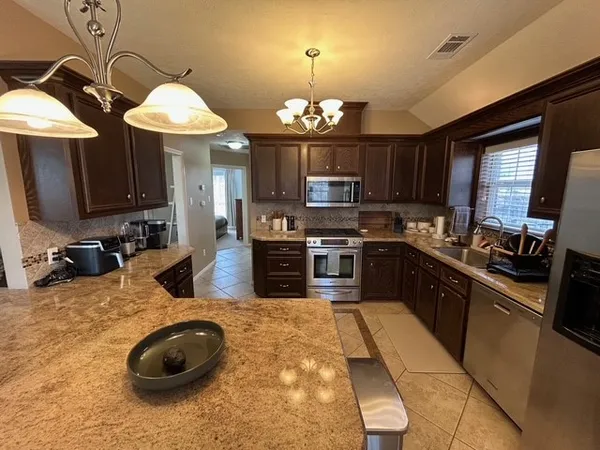 a kitchen with stainless steel appliances granite countertop a sink a stove and a microwave