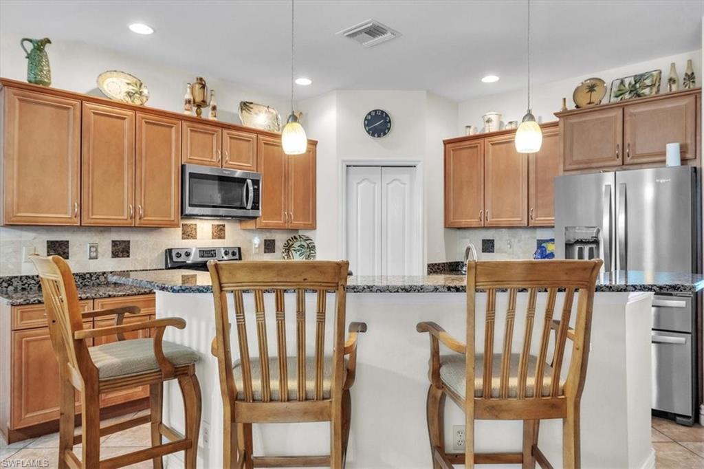 12914 Stone Tower Loop Fort Myers, FL 33913 - Photo 14 of 50 a kitchen with stainless steel appliances granite countertop a table chairs microwave and sink