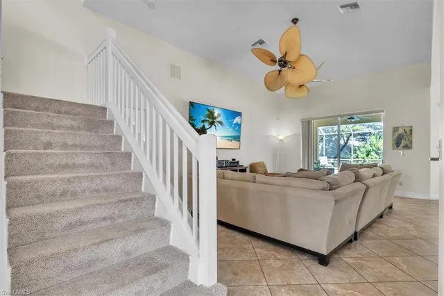 a living room with couches chandelier cabinets and a window