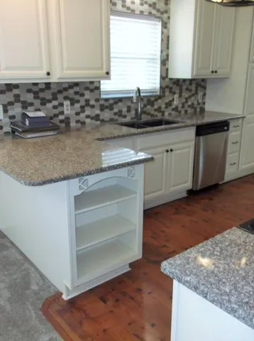 a kitchen with granite countertop a sink and a stove top oven