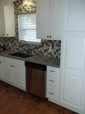 a kitchen with granite countertop white cabinets and sink