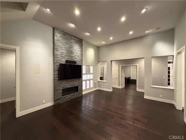 an empty room with wooden floor and a kitchen