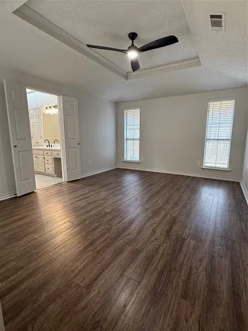 an empty room with wooden floor chandelier fan and windows