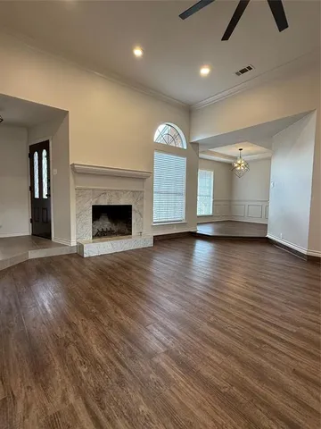 an empty room with wooden floor fireplace and windows