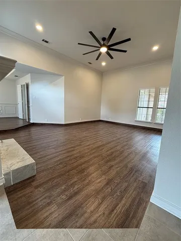 an empty room with wooden floor closet and windows