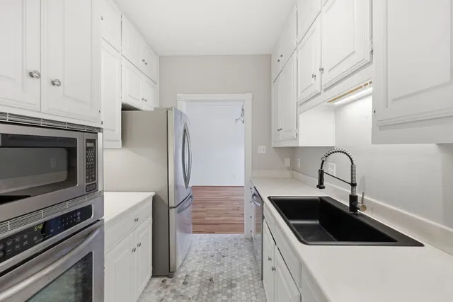 a view of an empty room with wooden floor and a bedroom