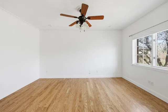 an empty room with window and ceiling fan