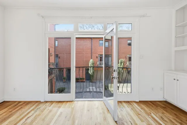 a view of an empty room with wooden floor fireplace and a window