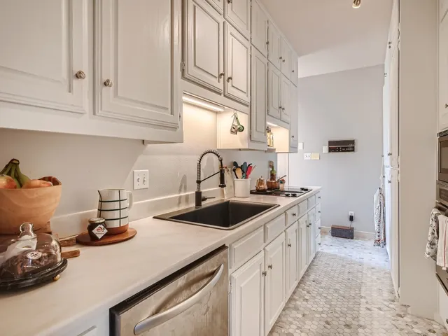 a kitchen with white cabinets and sink
