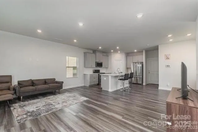 a living room with furniture kitchen view and a flat screen tv