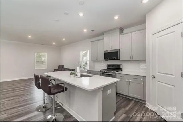 a kitchen with stainless steel appliances a stove a sink a microwave a refrigerator and cabinets