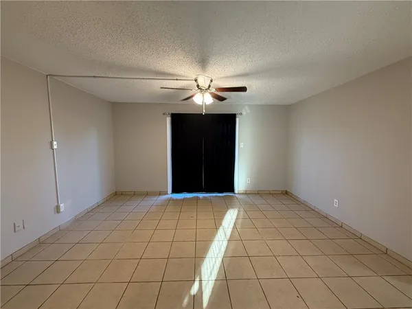 a view of an empty room and chandelier fan
