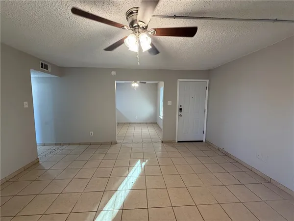 a view of an empty room with a ceiling fan and window