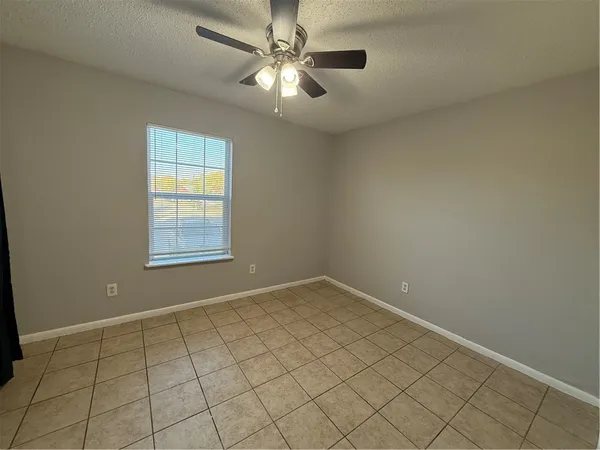 an empty room with windows and fan