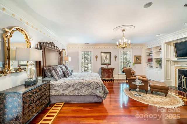 a bedroom with a bed a chandelier and flat screen tv