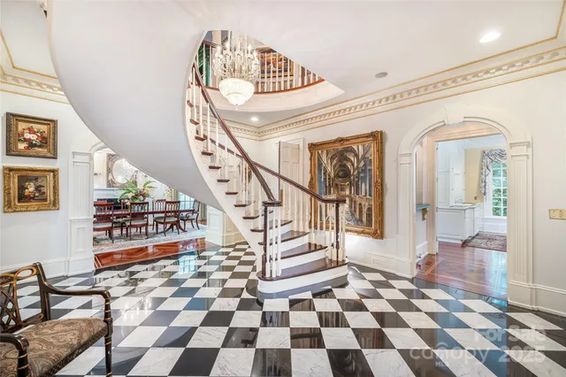 a living room with a black white checkered floor with a gaming machine and dining chair