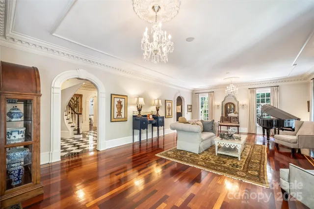 a living room with furniture a chandelier and wooden floor