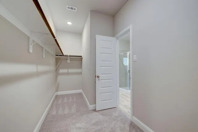 a view of a hallway with wooden floor and a bathroom
