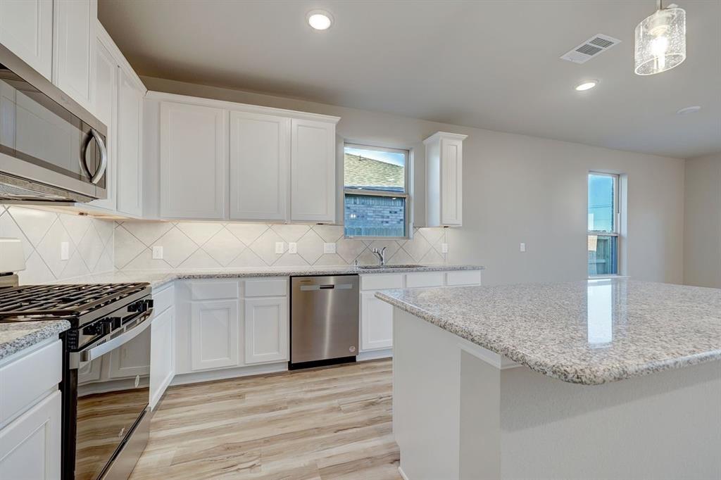 125 Toftrees Drive Cleburne, TX 76031 - Photo 7 of 22 a kitchen with granite countertop a sink a stove and cabinets