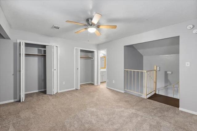 an empty room with closet and a ceiling fan