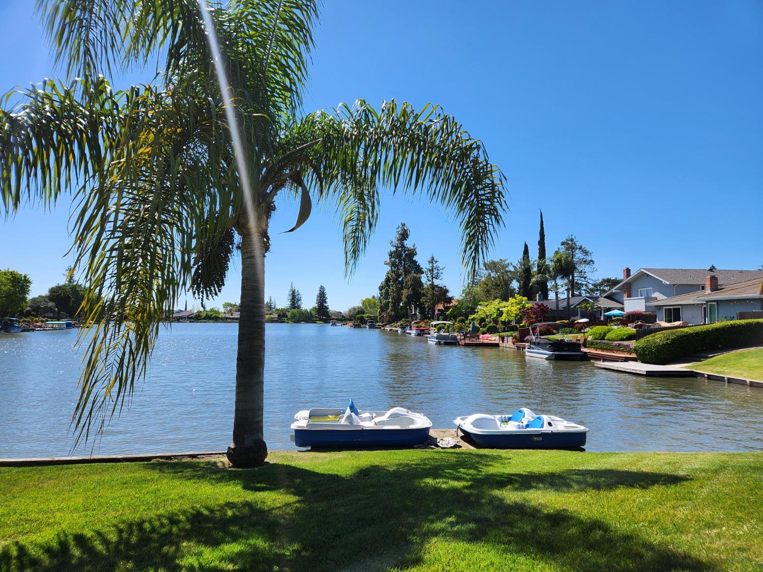 a view of a lake with lawn chairs and palm trees