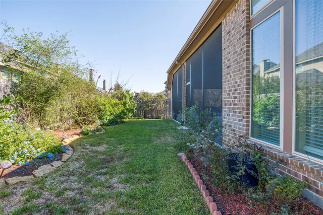 a backyard of a house with a floor to ceiling window and outdoor kitchen