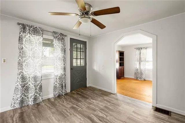 a view of empty room with wooden floor and fan