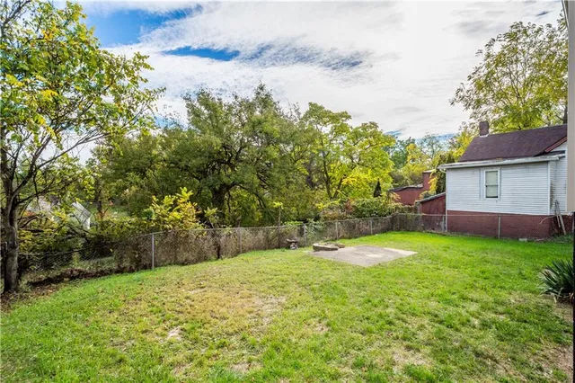 a view of backyard of house with wooden deck and large trees