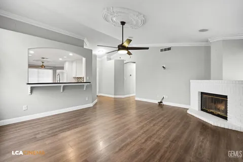 a view of an empty room with wooden floor a fireplace and a window