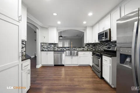 a kitchen with cabinets stainless steel appliances and wooden floor