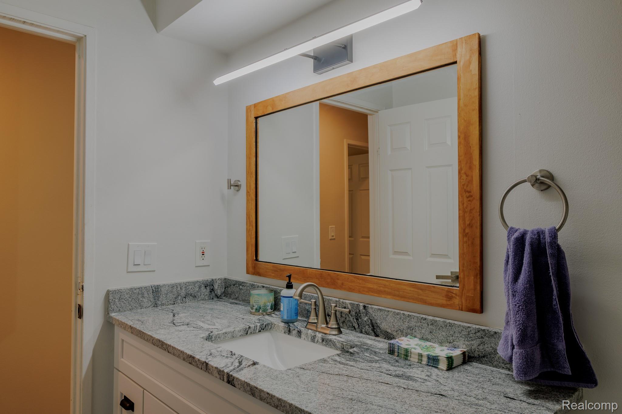 1989 Klingensmith Road, Unit 46 Bloomfield Hills, MI 48302 - Photo 17 of 41 Bathroom vanity with a gray patterned countertop, undermount sink, and brushed nickel faucet