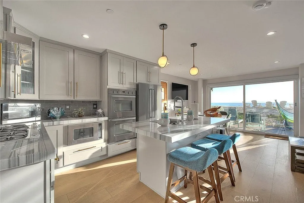 99 Surfside Avenue Surfside, CA 90743 - Photo 3 of 75 a kitchen with stainless steel appliances granite countertop a stove top oven a sink a dining table and chairs