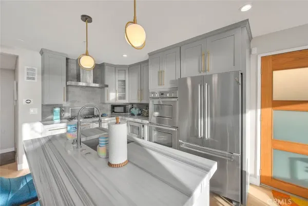 a kitchen with a refrigerator a stove a sink dishwasher a dining table and chairs with wooden floor