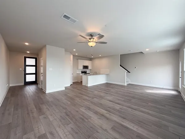 a view of an empty room with a window and wooden floor
