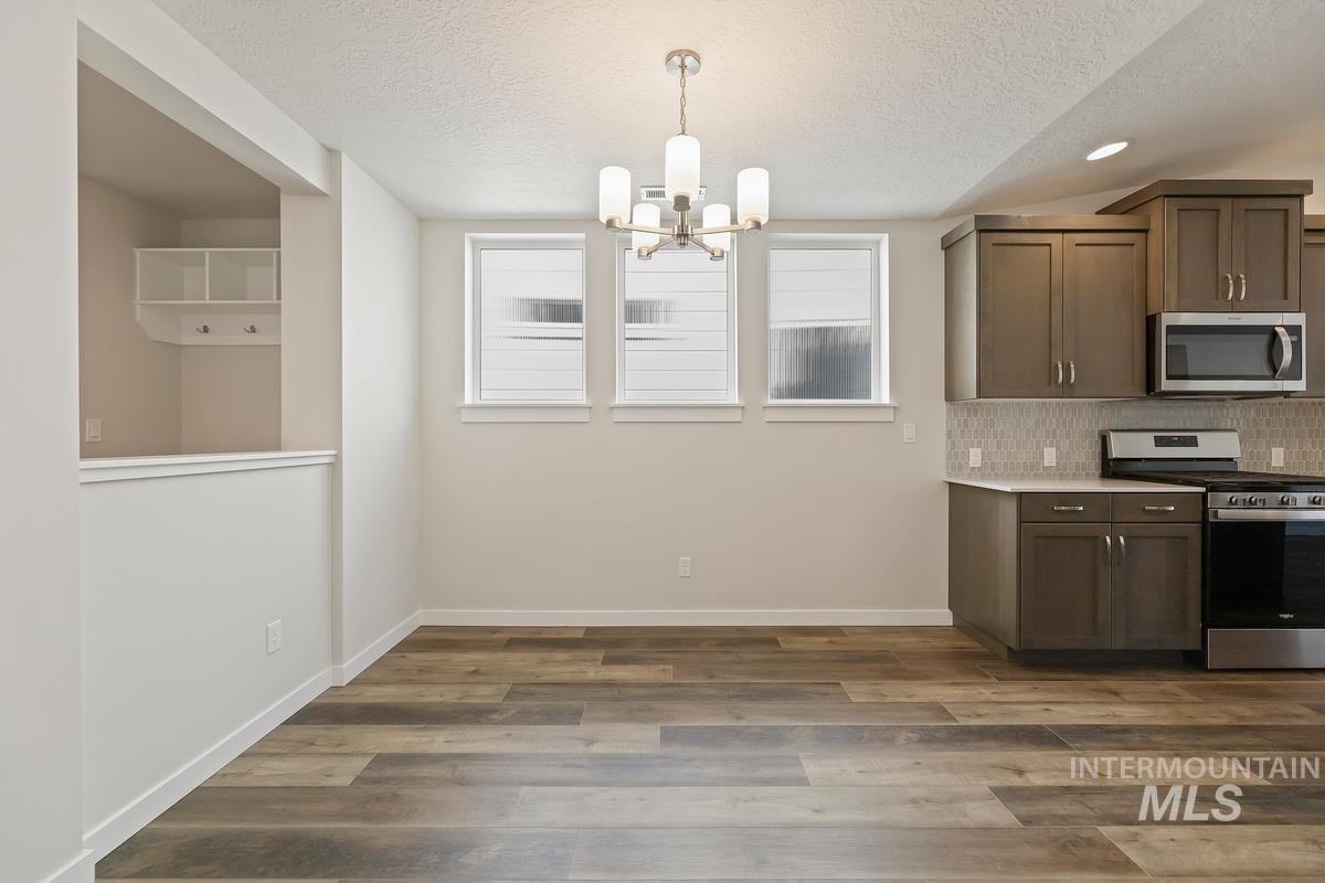 212 East Radiant Ridge Drive Meridian, ID 83642 - Photo 11 of 36 Kitchen featuring stainless steel appliances, dark wood-type flooring, hanging lights, a textured ceiling, and tasteful backsplash