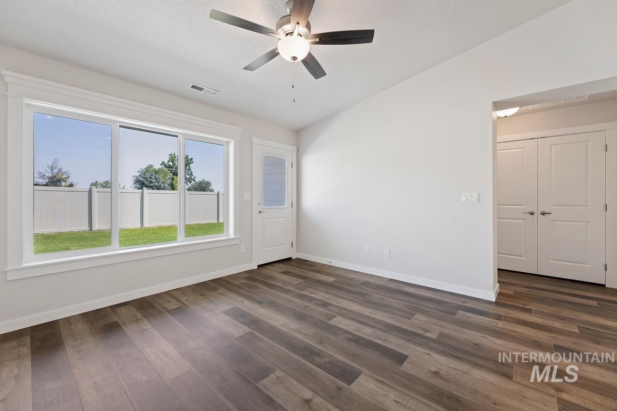 212 East Radiant Ridge Drive Meridian, ID 83642 - Photo 12 of 36 Empty room with vaulted ceiling, ceiling fan, and dark wood-style flooring