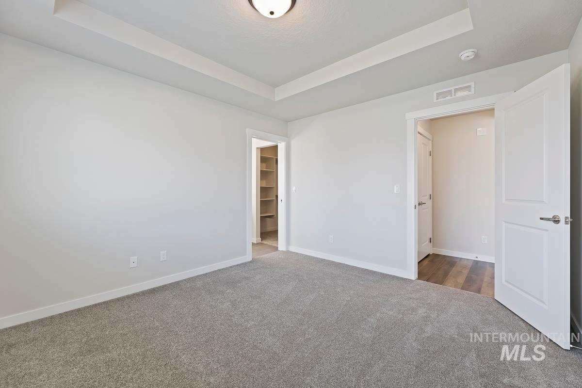 212 East Radiant Ridge Drive Meridian, ID 83642 - Photo 16 of 36 Unfurnished bedroom featuring a tray ceiling, a spacious closet, and carpet floors