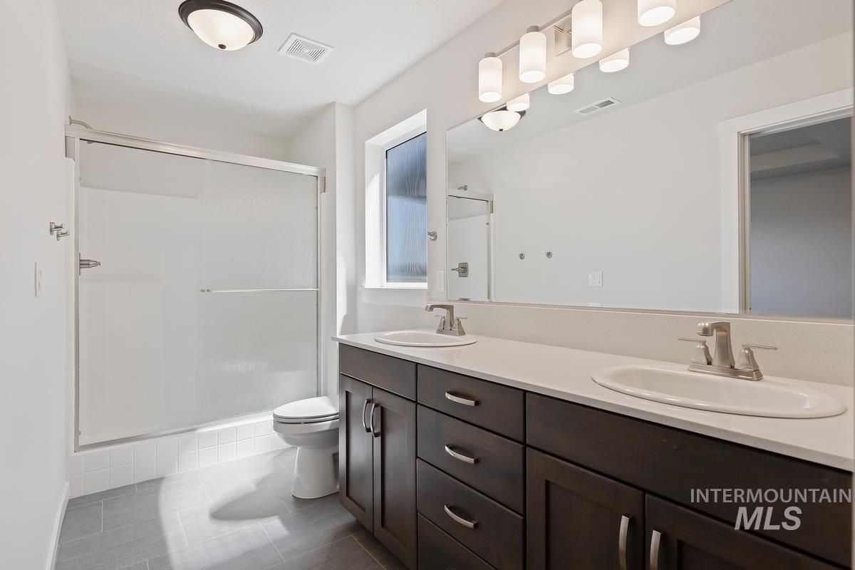 212 East Radiant Ridge Drive Meridian, ID 83642 - Photo 18 of 36 Bathroom with a stall shower, double vanity, and dark tile patterned flooring