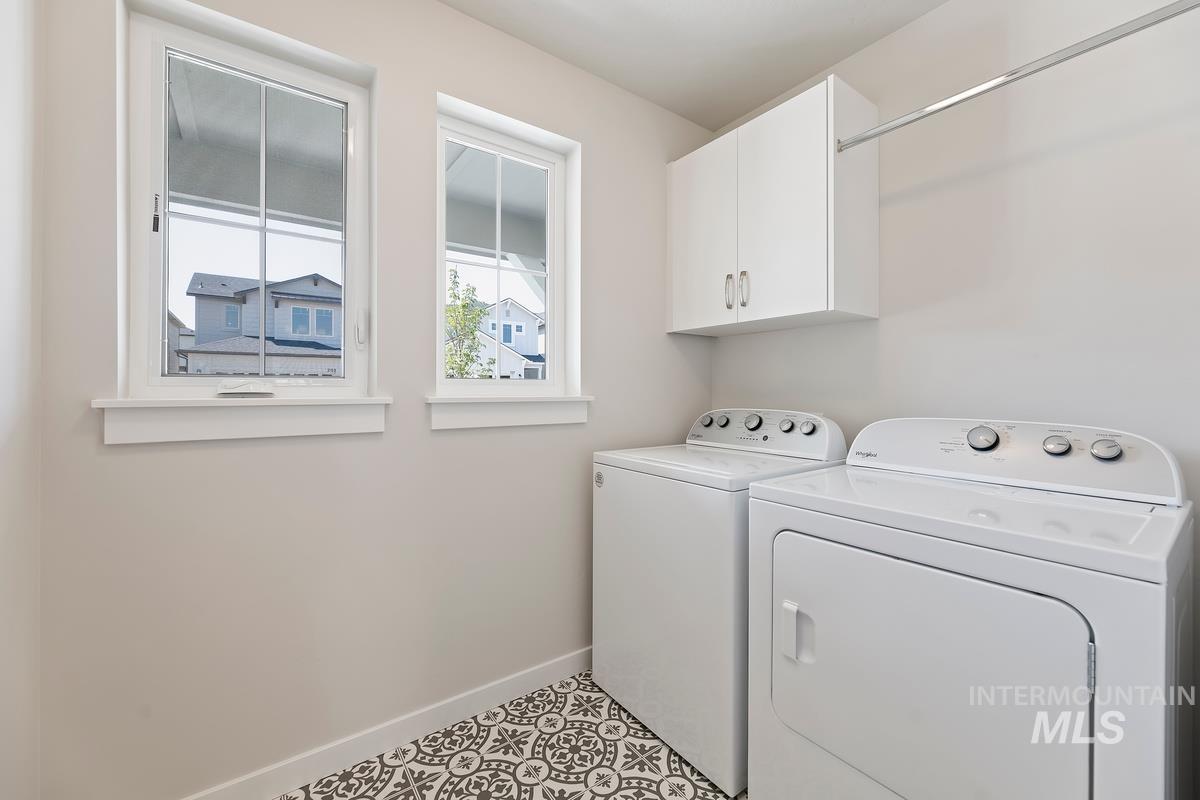 212 East Radiant Ridge Drive Meridian, ID 83642 - Photo 26 of 36 Laundry area featuring washer and dryer, light tile patterned floors, and cabinet space