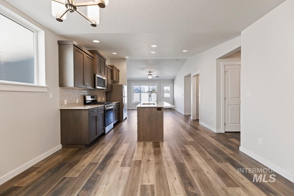 212 East Radiant Ridge Drive Meridian, ID 83642 - Photo 3 of 36 Kitchen with stainless steel appliances, an island with sink, dark wood finished floors, dark wood finish cabinetry, and a textured ceiling
