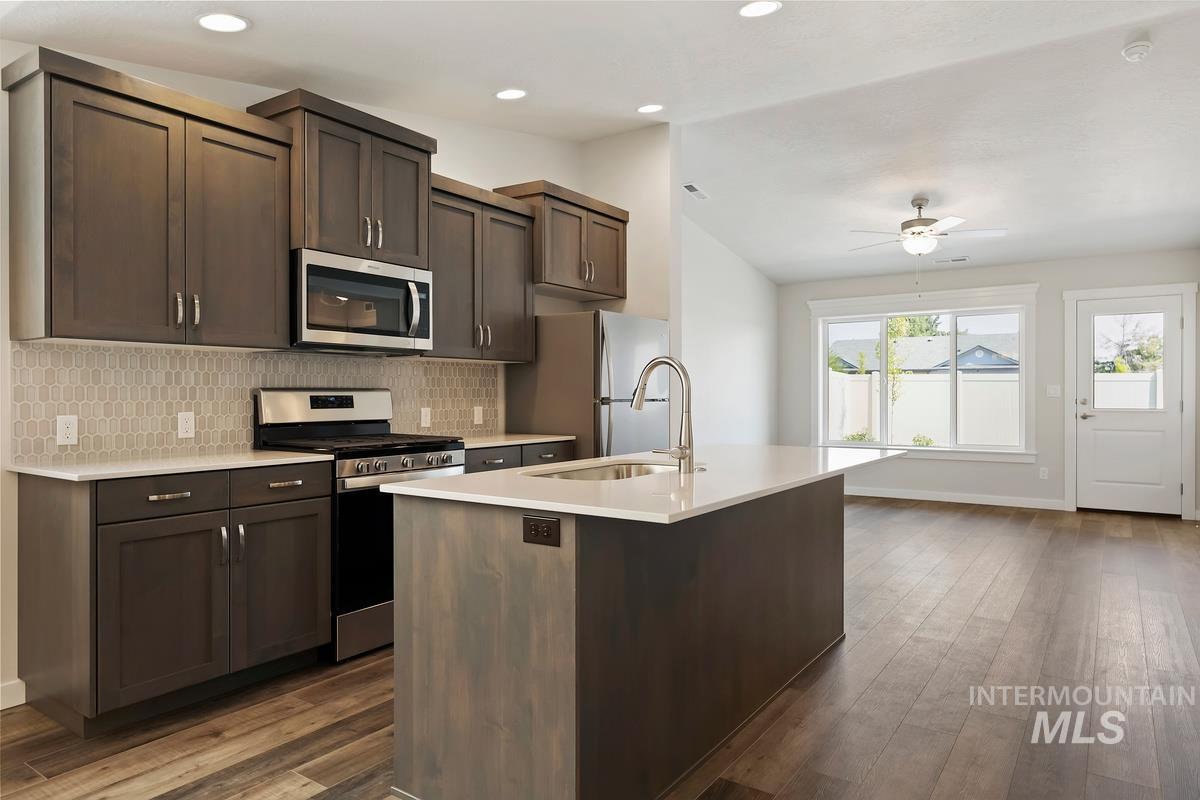 212 East Radiant Ridge Drive Meridian, ID 83642 - Photo 4 of 36 Kitchen featuring stainless steel appliances, dark wood finish cabinetry, lofted ceiling, dark wood-type flooring, and a ceiling fan