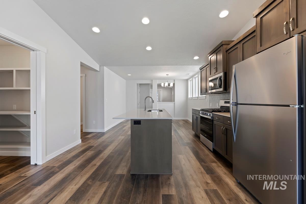 212 East Radiant Ridge Drive Meridian, ID 83642 - Photo 7 of 36 Kitchen with stainless steel appliances, dark wood finish cabinetry, a center island with sink, and dark wood-type flooring