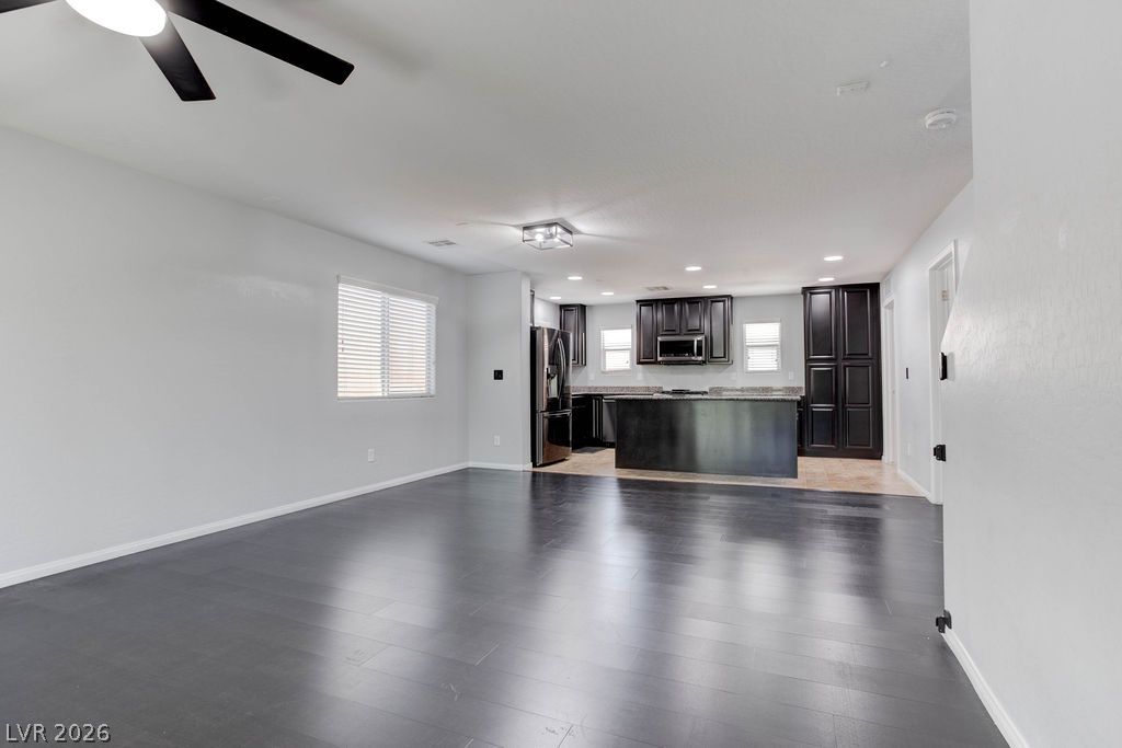 7724 Vibrant Thread Court Las Vegas, NV 89149 - Photo 18 of 43 Sleek dark wood flooring flows from the living area into a modern kitchen, creating an inviting open-concept space.