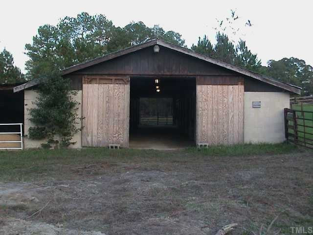 5405 Castlebrook Drive Raleigh, NC 27604 - Photo 9 of 12 Cement block barn, with partial view of 18'x70' covered storage area to the left. Additional 6 stalls and a tractor parking shelter are along the length of the barn to the left.